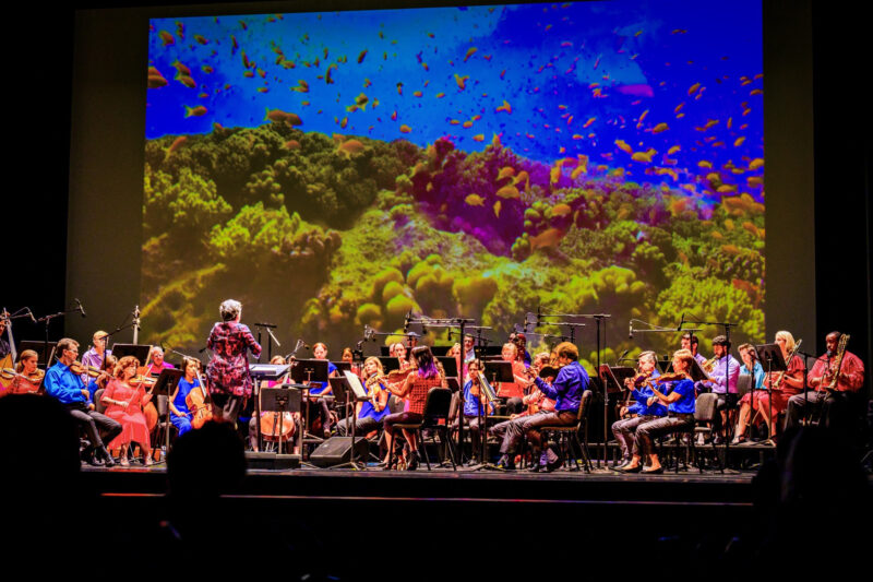 Mei Ann Chen conducts ROCO at Miller Outdoor Theatre with immersive marine life visuals in the background